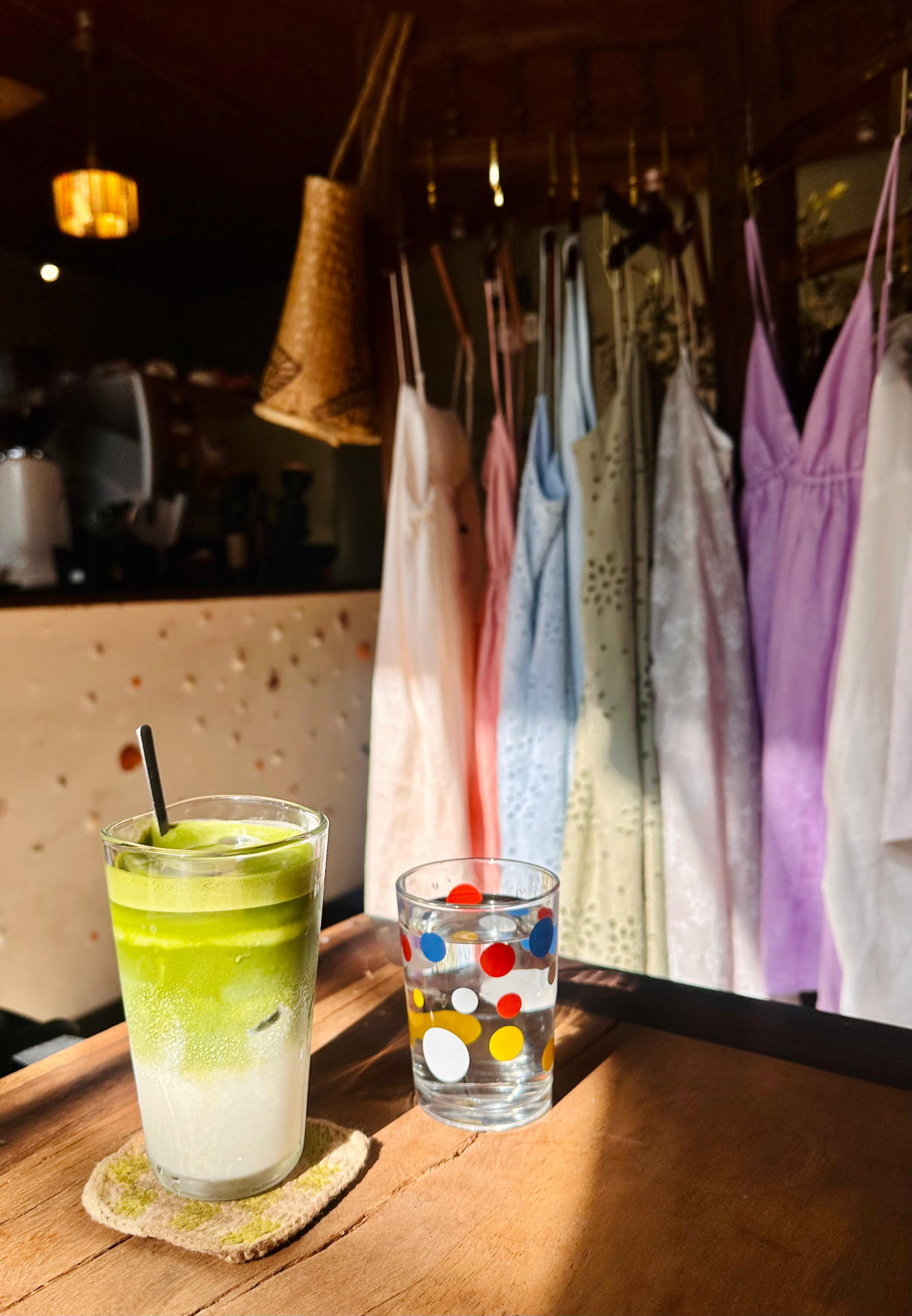 Matcha drink on a sunlit table beside a display of Lele Linen dresses at Thong Dong Local Cafe