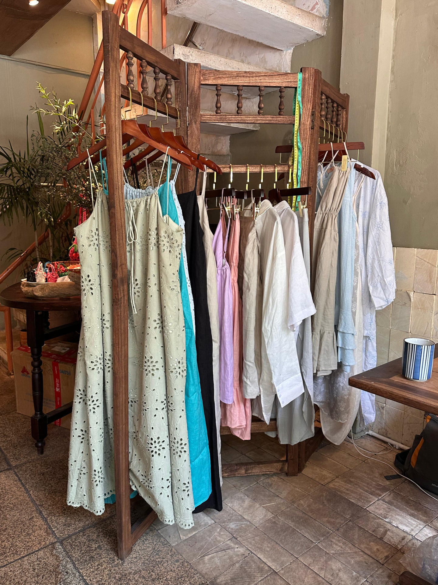 Wooden clothing rack displaying Lele Linen dresses and shirts at Thong Dong Local Cafe